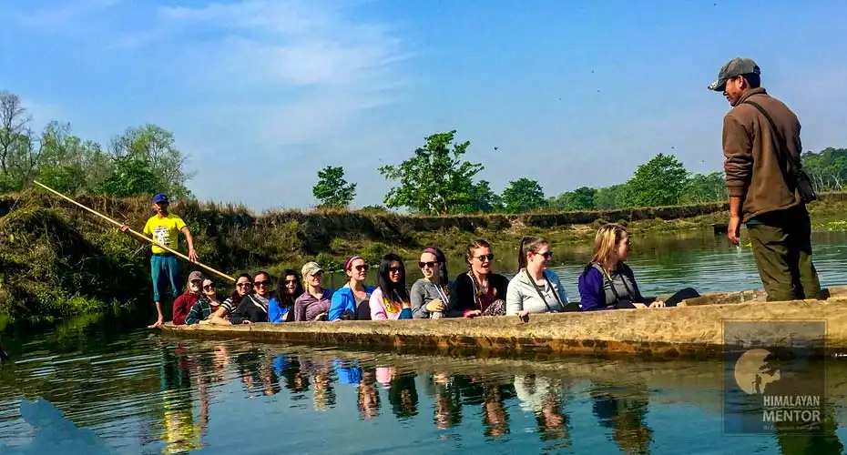 Happy travelers are taking a dugout canoe ride in Rapti River